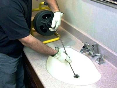 Plombier débouche un lavabo avec un furet